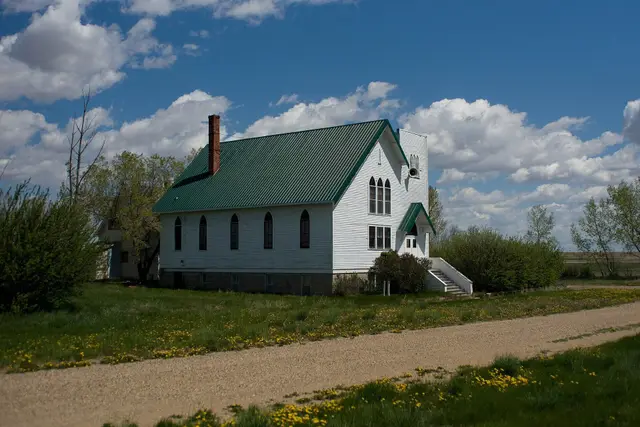 White church with green roof on a gravel road